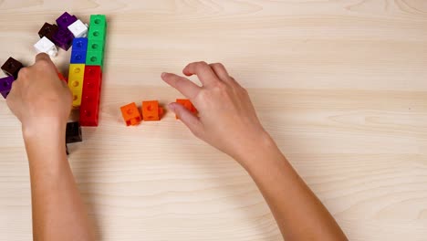 hands assembling colorful linking cubes on table