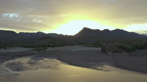 Vista-Aérea-De-La-Puesta-De-Sol-De-Arizona-Dorada-Sobre-Un-Pequeño-Cuerpo-De-Agua