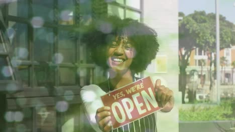 Animation-of-portrait-of-african-american-female-shop-assistant-with-open-sign-over-spots