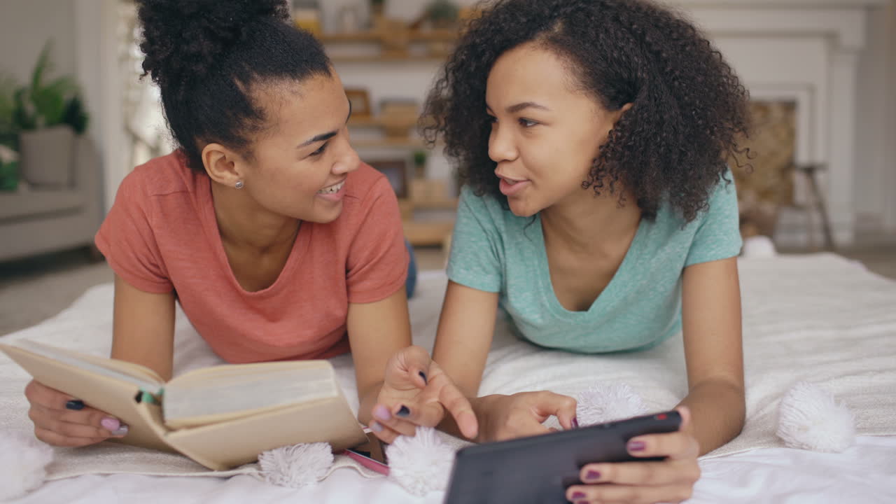 Two girls enjoying time together, reading and using tablet
