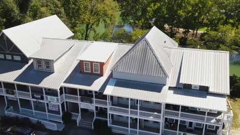 aerial fly over of boutiques, revealing trees and water behind the charming shops at old town helena, alabama