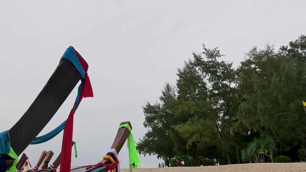 Vibrant boat prows with colorful fabric set against a backdrop of dense green trees.