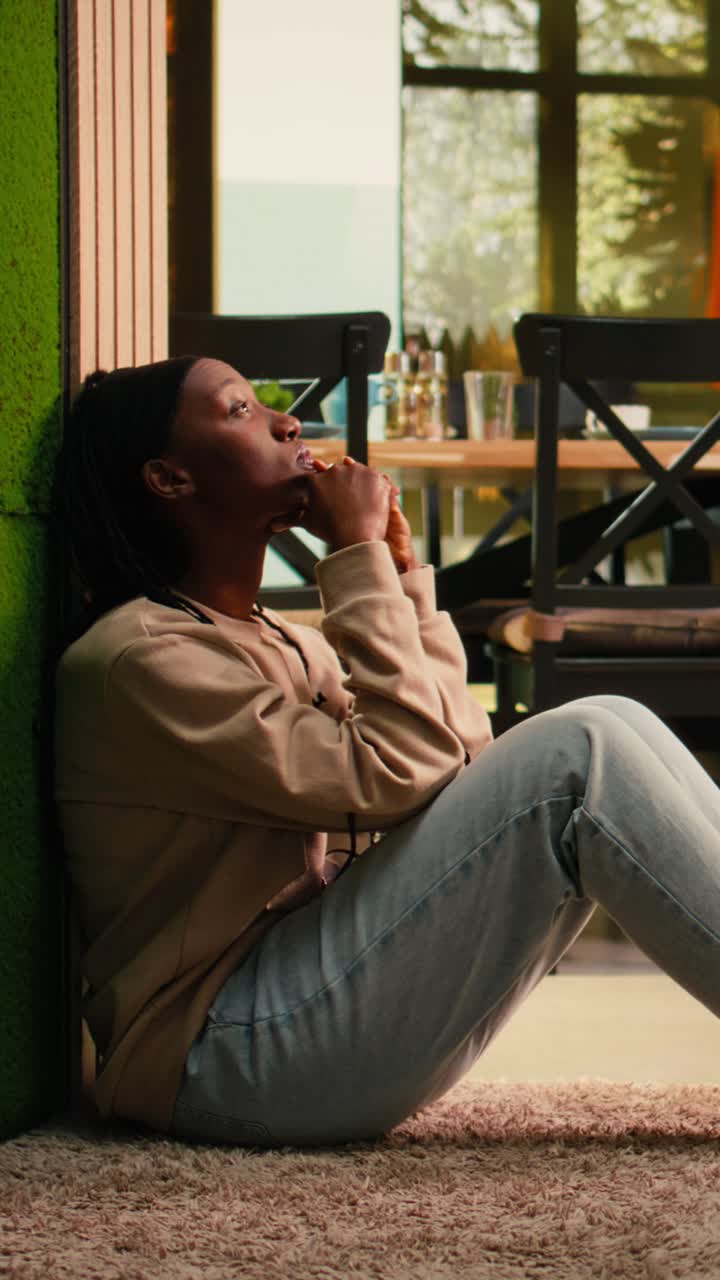Vertical Video Depressed African American woman sitting alone on the floor at home