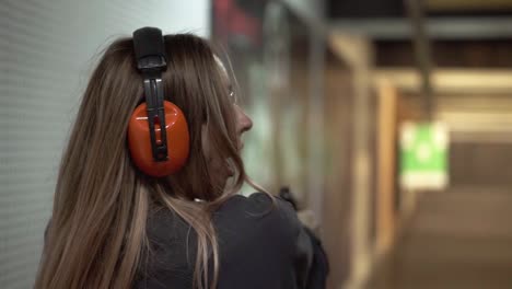 woman with pistol weapon in hands at shooting range with target, excited and surprised