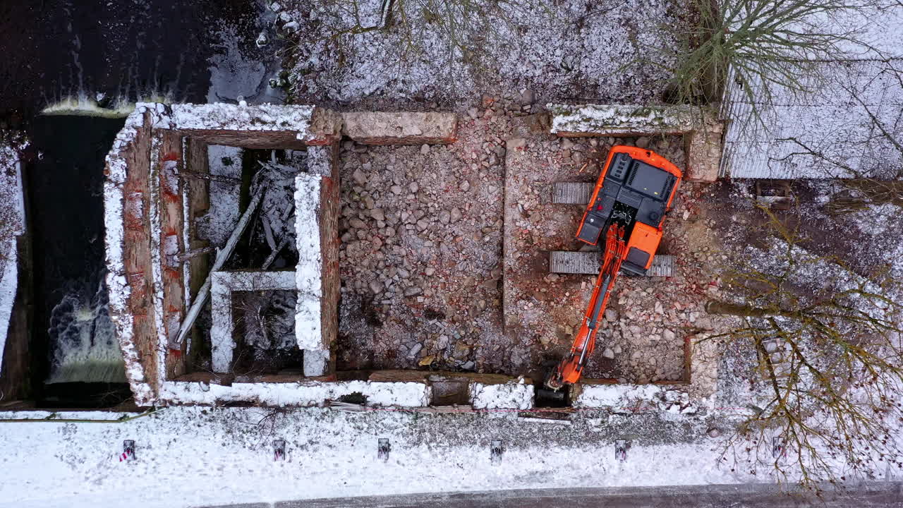 Aerial view looking down over excavator machinery inside the ruins of old water mill