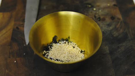 chef adding sesame into bowl with seaweed and salt for tasty sauce,close up