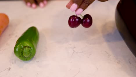 black woman hand is seductively grabbing cherry vegetables on a marble kitchen table