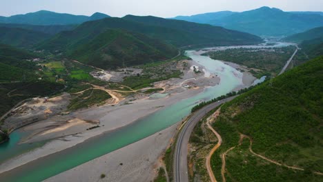 Wild-River-Flowing-from-the-Mountains-in-the-Wide-Valley-with-Greenery,-Turquoise-Water-against-a-Beautiful-Background-in-Albania