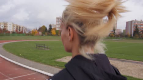 cerca de una mujer rubia joven y deportiva corriendo en cámara lenta en una pista de atletismo