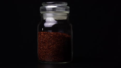 hierbas de té en un vaso contra un fondo oscuro