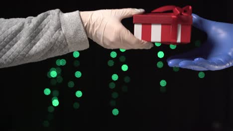 higiene xmas coronavirus. entrega de regalos. pandemia nuevo año 2021. la nueva norma. manos con guantes de protección intercambian un regalo envuelto en una caja