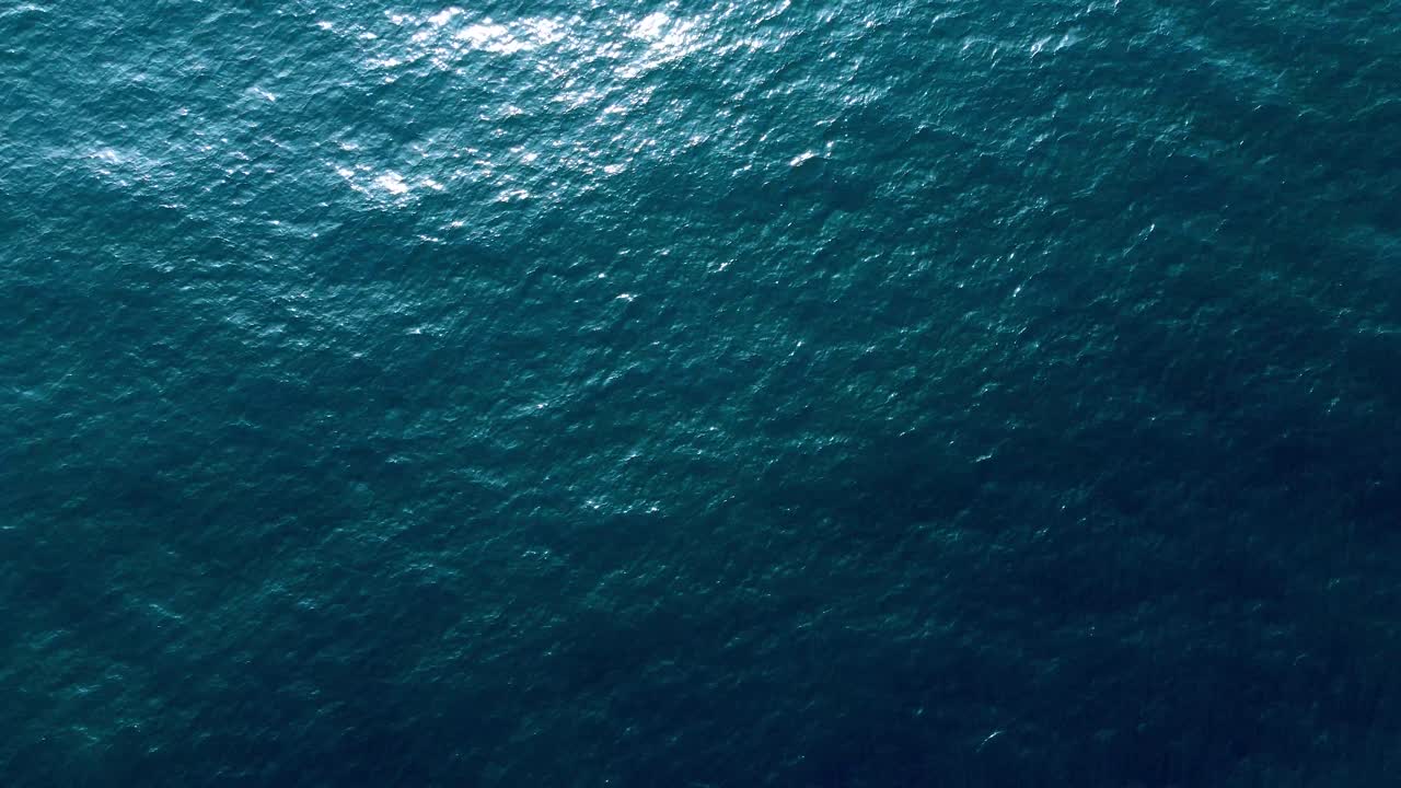 Ripresa aerea della bellissima superficie liscia di un mare limpido e blu scuro.