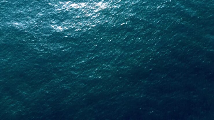 Ripresa aerea della bellissima superficie liscia di un mare limpido e blu scuro.