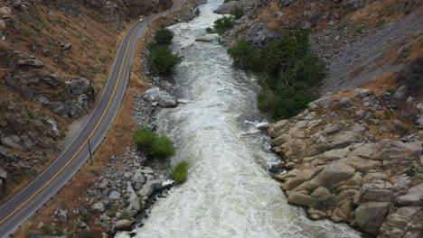 quick-aerial-dolly-down-the-kern-river-on-highway-178-from-lake-isabella-dam-in-bakersfield-during-a-raging-flood-with-quick-turbulent-water-rushing-hard-and-covering-trees