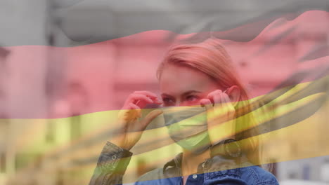 animation of flag of germany waving over woman wearing face mask during covid 19 pandemic