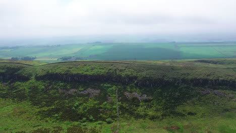 Aerial-tracking-shot-along-a-cliff-section-of-Hadrians-Wall,-on-a-bright-day