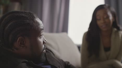 couple at home sitting on sofa in lounge with couple making up after argument