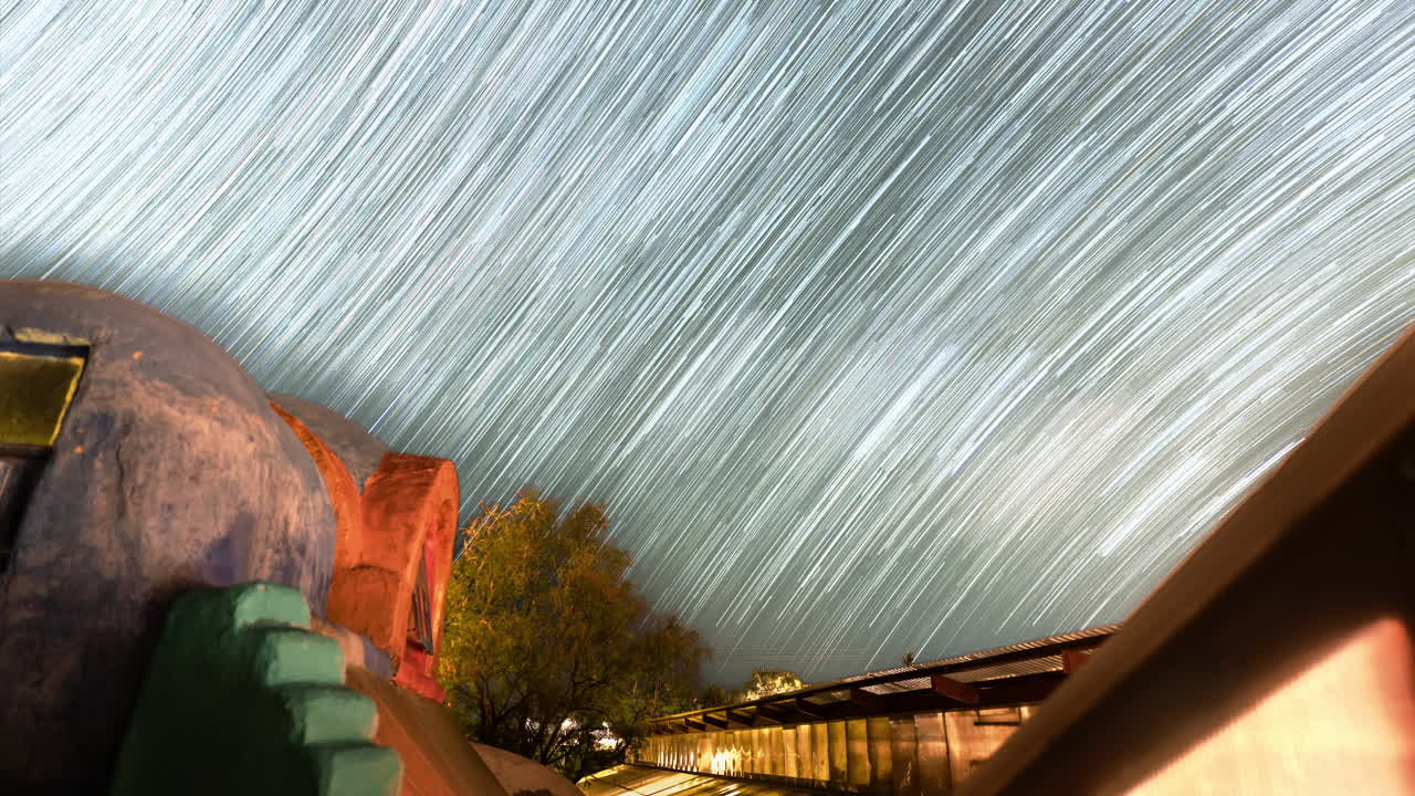 Star trail Timelapse of the night sky streaking over a southwestern building