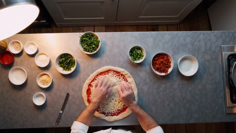 overhead view of hands preparing a pizza in a kitchen