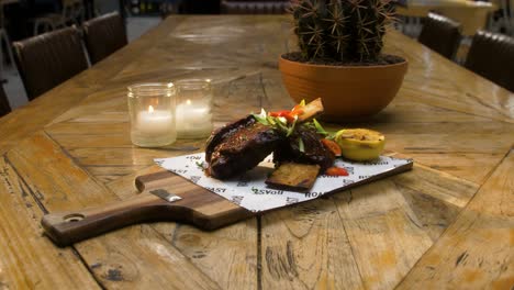 bistec en un hueso se sirve en una mesa de madera con velas