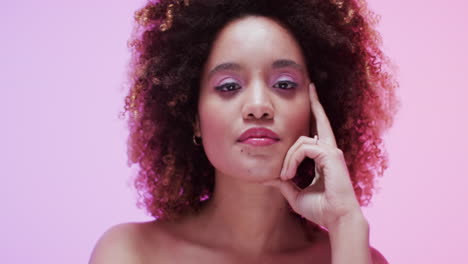 mujer biracial con cabello oscuro en luz rosa, cámara lenta