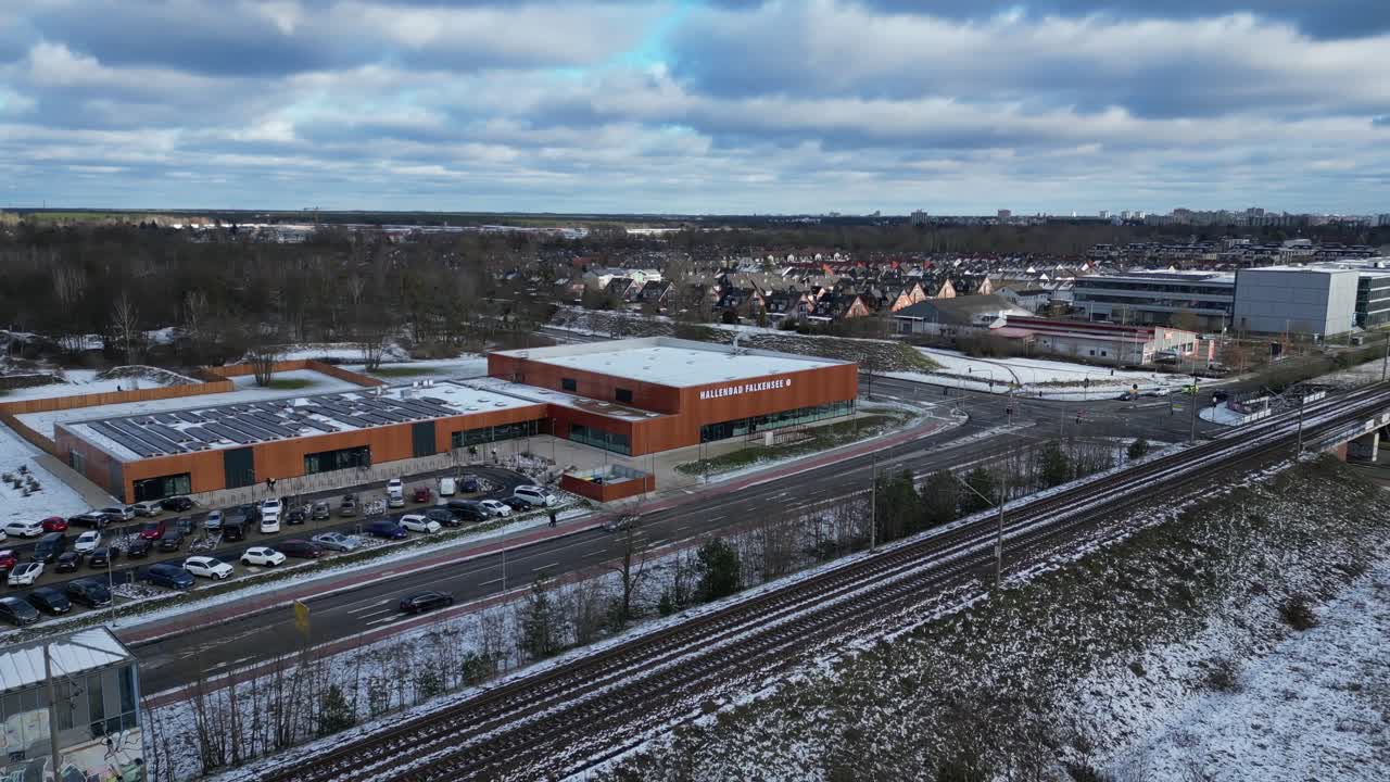 Indoor swimming pool with solar panels surrounded by snow and suburban homes in Falkensee Germany. Gorgeous aerial view flight wide orbit overview drone