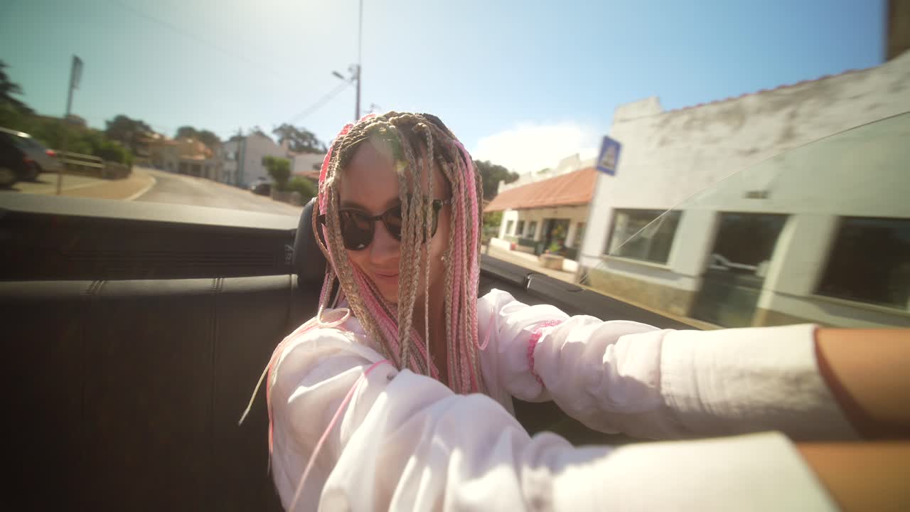Woman with braids enjoying a sunny convertible ride