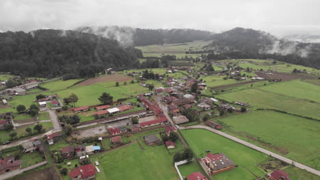 aerial orbit of a small town surrounded by clouds, trees and mountains in valle de bravo, mexico