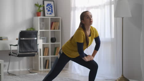 La-Mujer-Joven-Está-En-Cuclillas-En-El-Entrenamiento-Matutino-En-Casa-Haciendo-Gimnasia-Y-Aeróbicos-Para-Una-Buena-Actividad-Física-Retrato-Medio-Interior