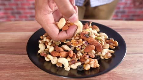 person picking cashews from a plate of mixed nuts