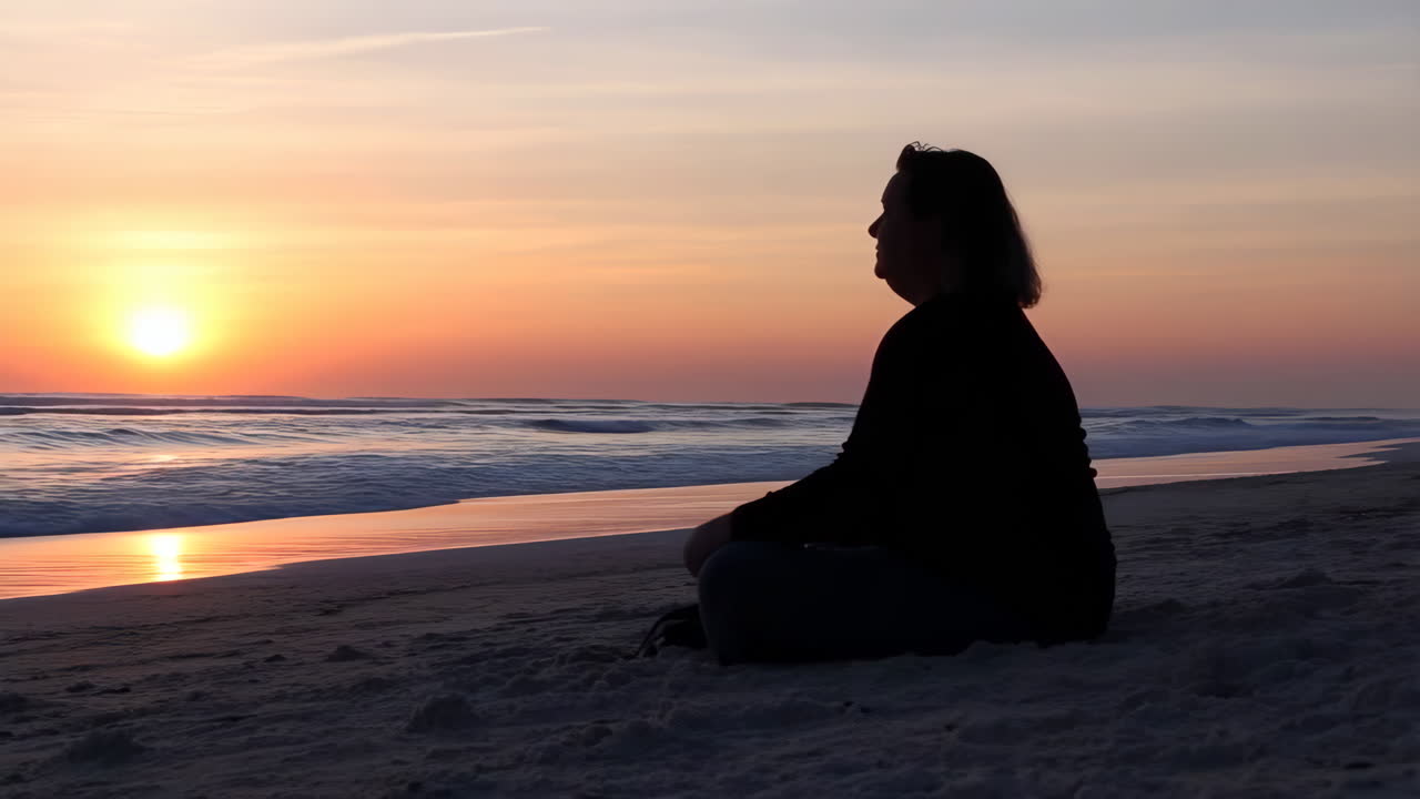 Silhouette of a person meditating on a beach at sunset