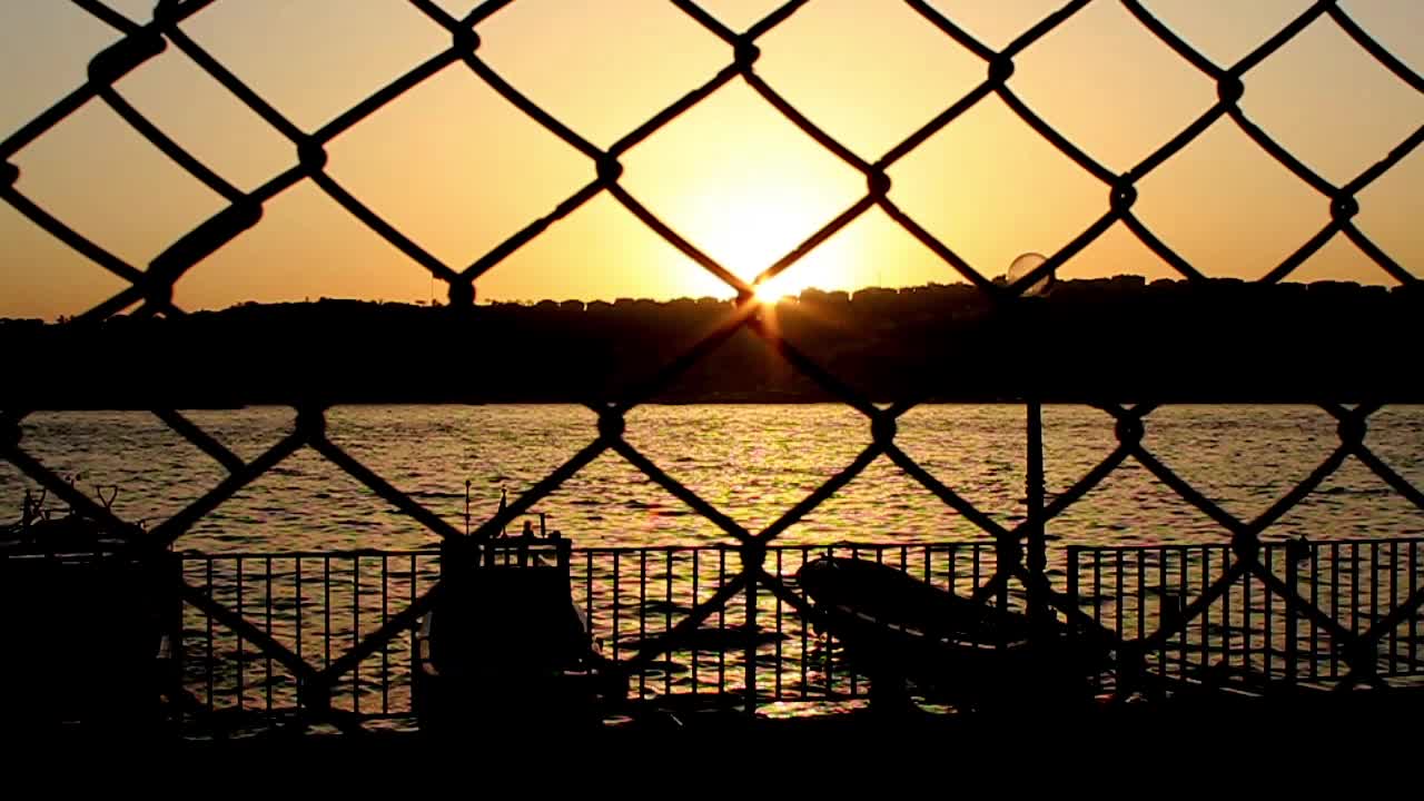 철망으로 바다와 해가 지는 것