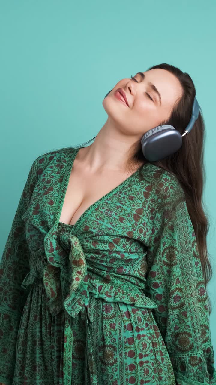 Happy woman dancing while listening to music using headphones