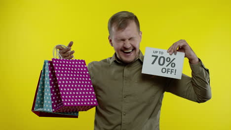 man showing up to 70 percent off inscription and shopping bags, looking satisfied with low prices