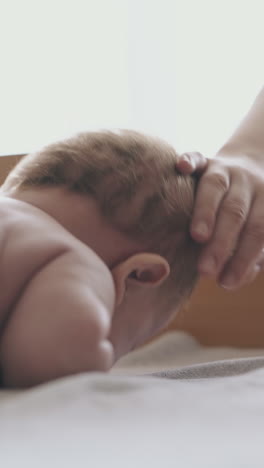 professional pediatrician practices infant boy massage and mother pets fair haired son head close view