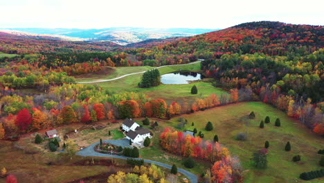 aerial view of serene autumn landscape, multicolored forest and a ranch in rural countryside, drone shot