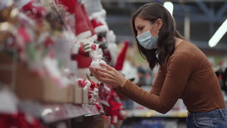 A-woman-in-a-protective-mask-in-a-jewelry-store-and-garlands-with-toys-for-Christmas-trees-and-at-home.-Christmas-garlands-and-decor