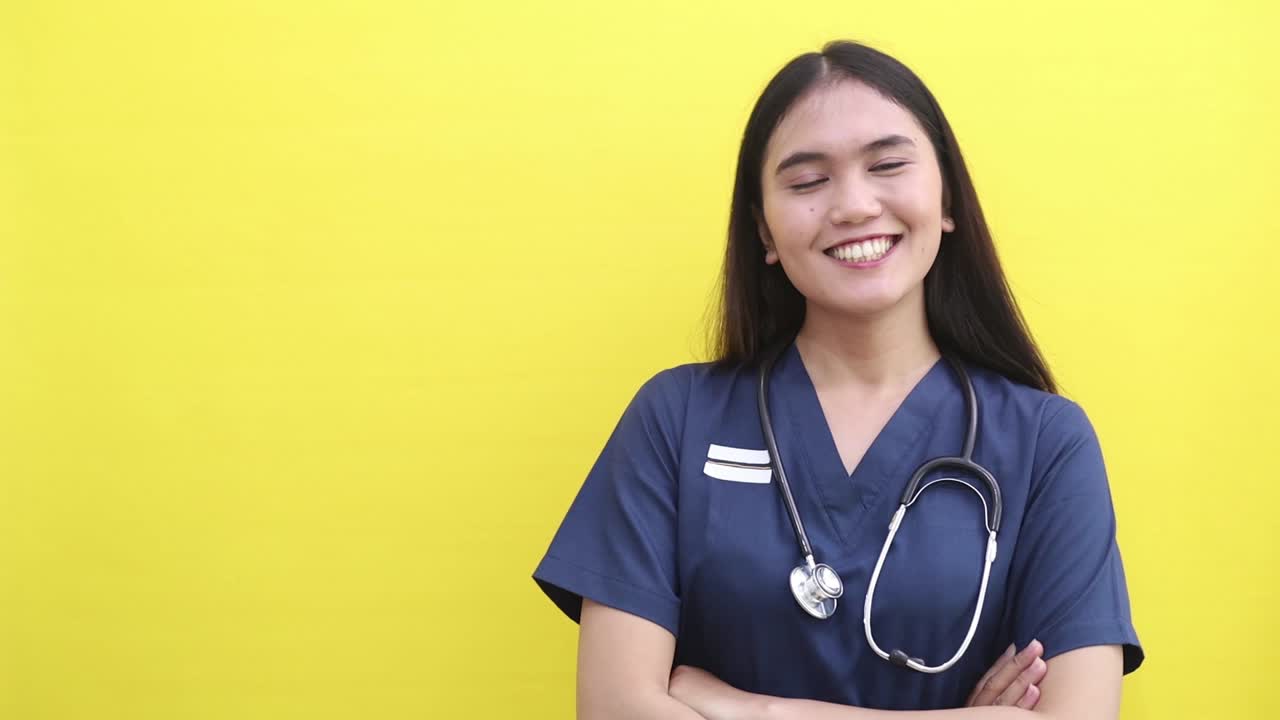 Amazed surprised Asian doctor woman posing isolated on yellow color background studio. Pointing index finger aside say wow