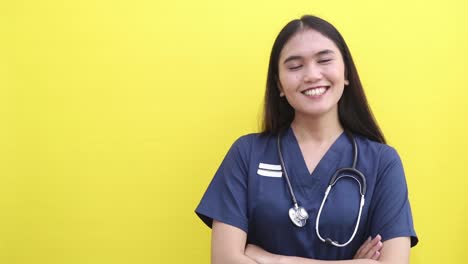 amazed surprised asian doctor woman posing isolated on yellow color background studio. pointing index finger aside say wow