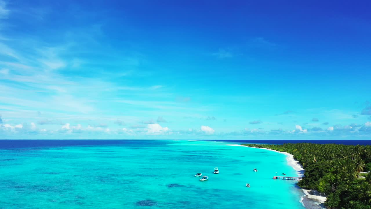 Paradise tropical bay full of anchored boats close to pier of tropical island with long white beach and palm trees forest in Bahamas