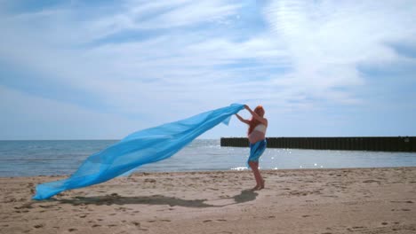 pregnant woman having fun with blue cloth flying in wind. pregnant woman beach