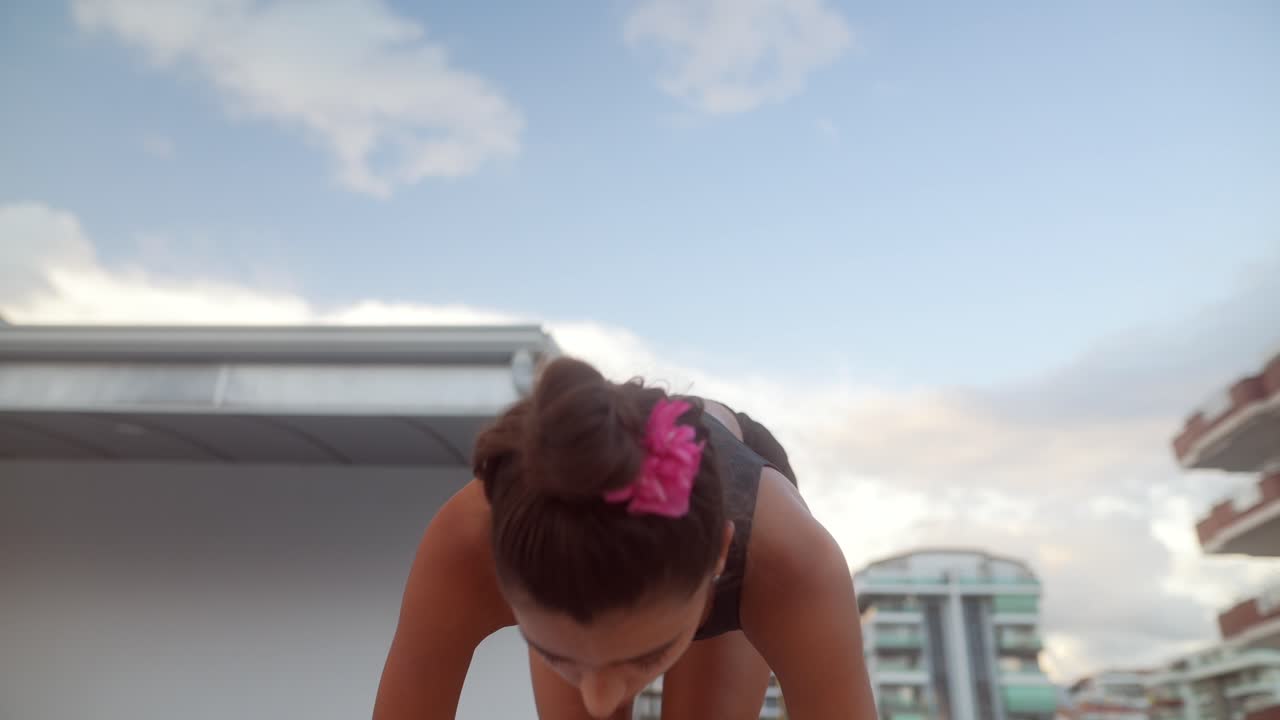mujer haciendo yoga en el techo cerca de una piscina