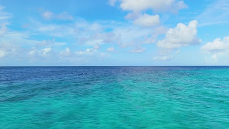 arrecife de coral con aguas arenosas bajo un cielo azul con nubes esponjosas