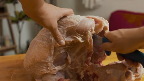 cutting turkey meat with kitchen knife on wooden cut board