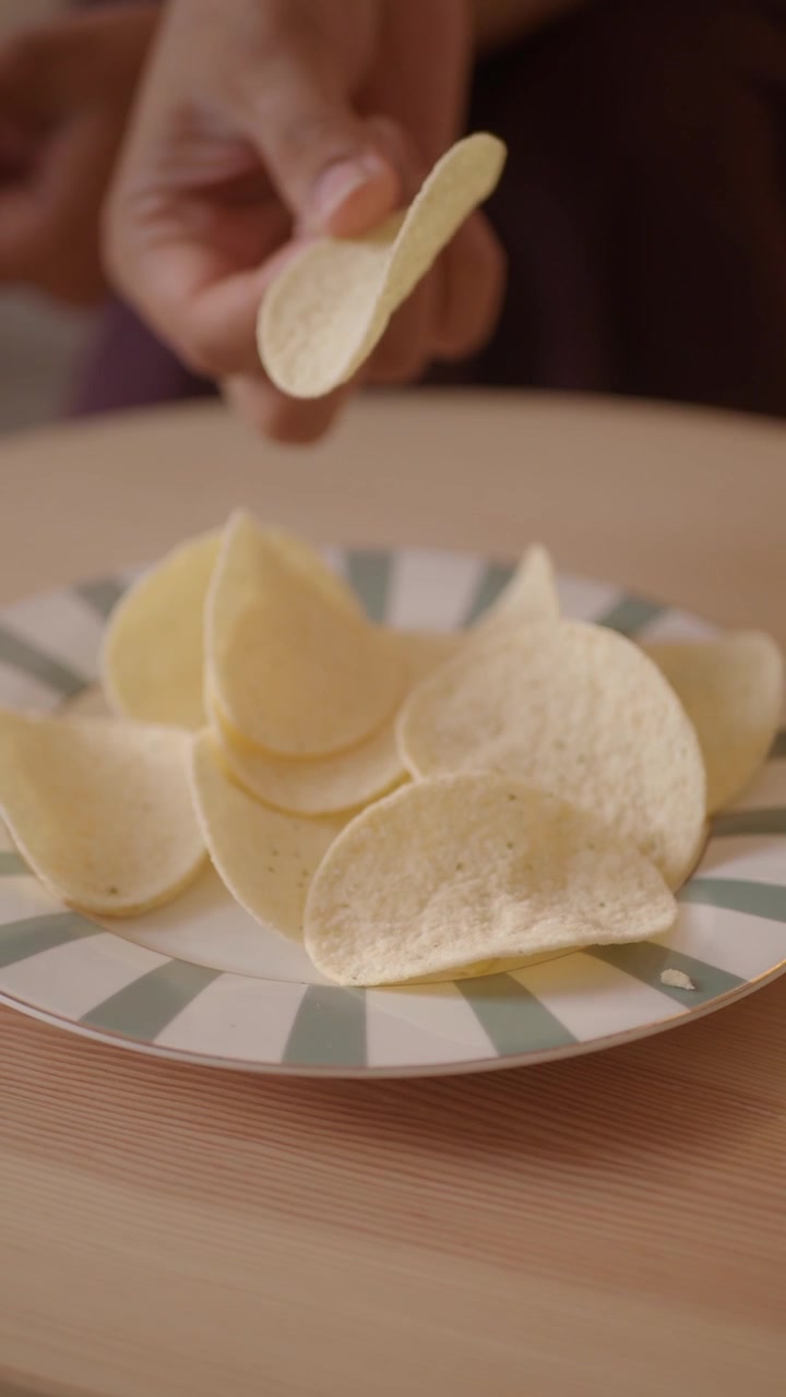 Person Picking Up Potato Chip From Plate