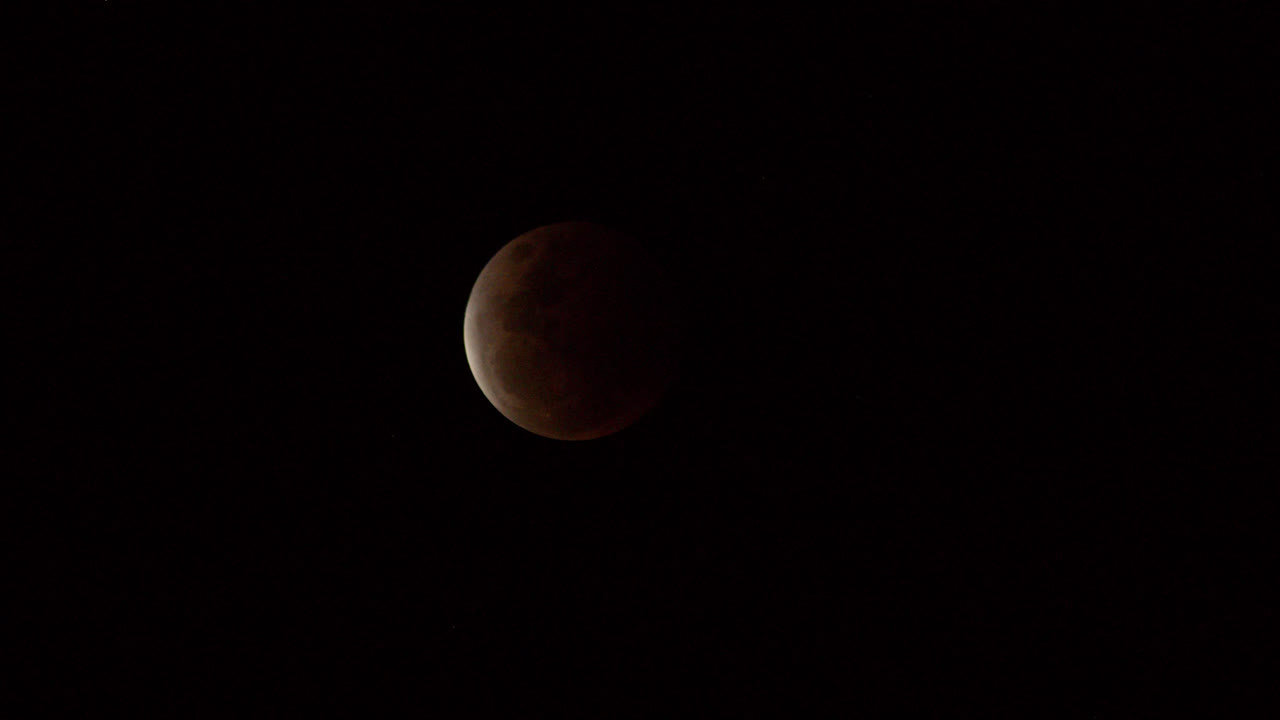 A waxing crescent moon, with a sliver of light illuminating one side of the moons surface against the dark black sky at night