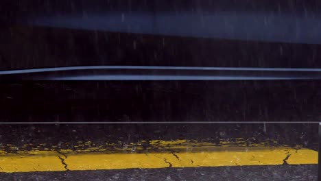 rain drops falling on asphalt with yellow crosswalk and car passing by, handheld