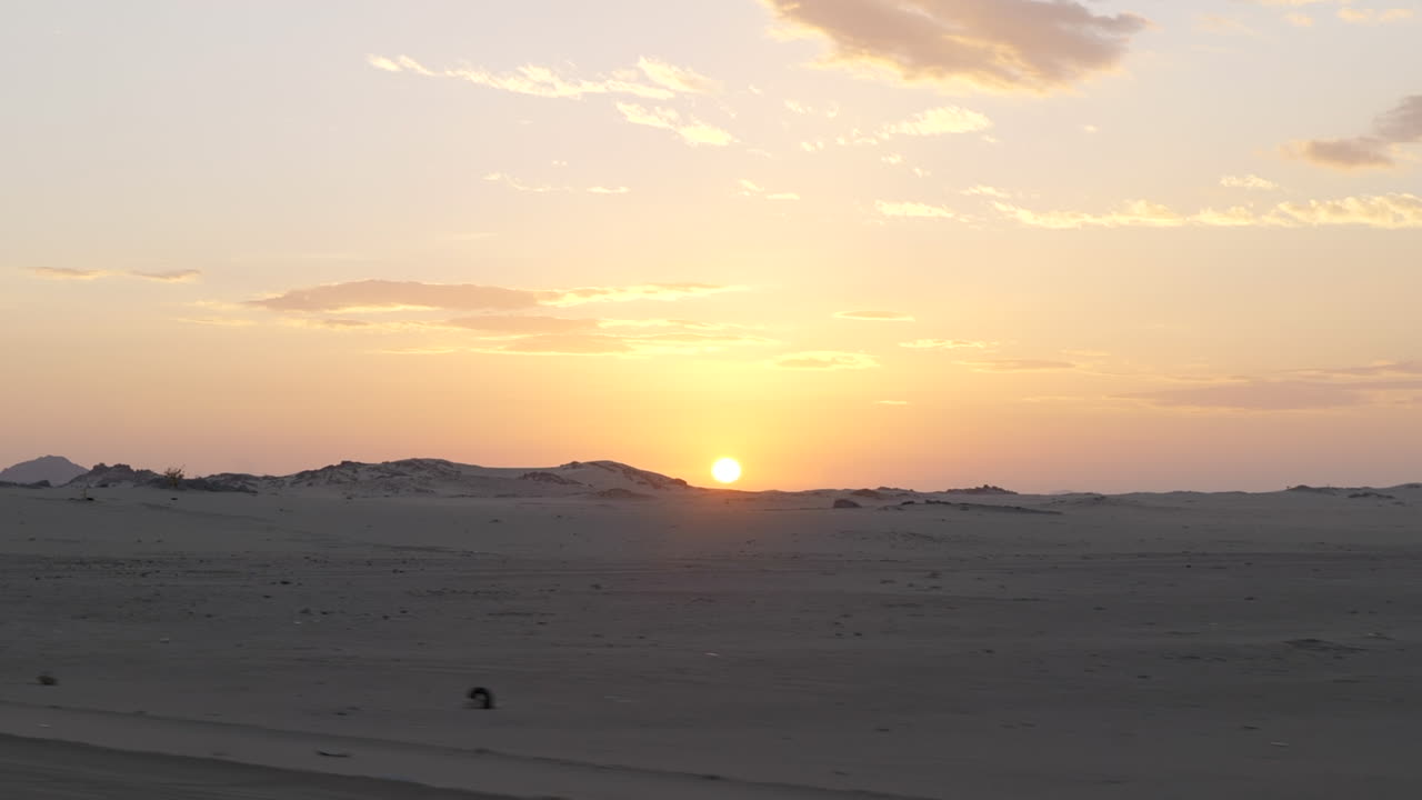 conduciendo por una carretera desértica con impresionantes vistas de las dunas de arena y la puesta de sol en el fondo