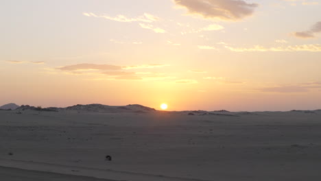 driving on desert road with stunning view of sand dunes and sun setting down in background