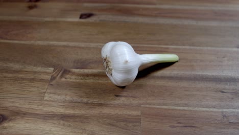 whole head of garlic without peeling and with its stem, on wooden kitchen table